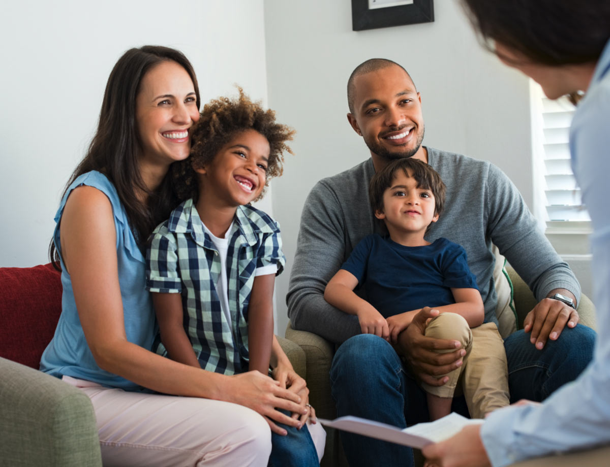 an image of two parents holding their children on their laps listening to a physician sitting with them