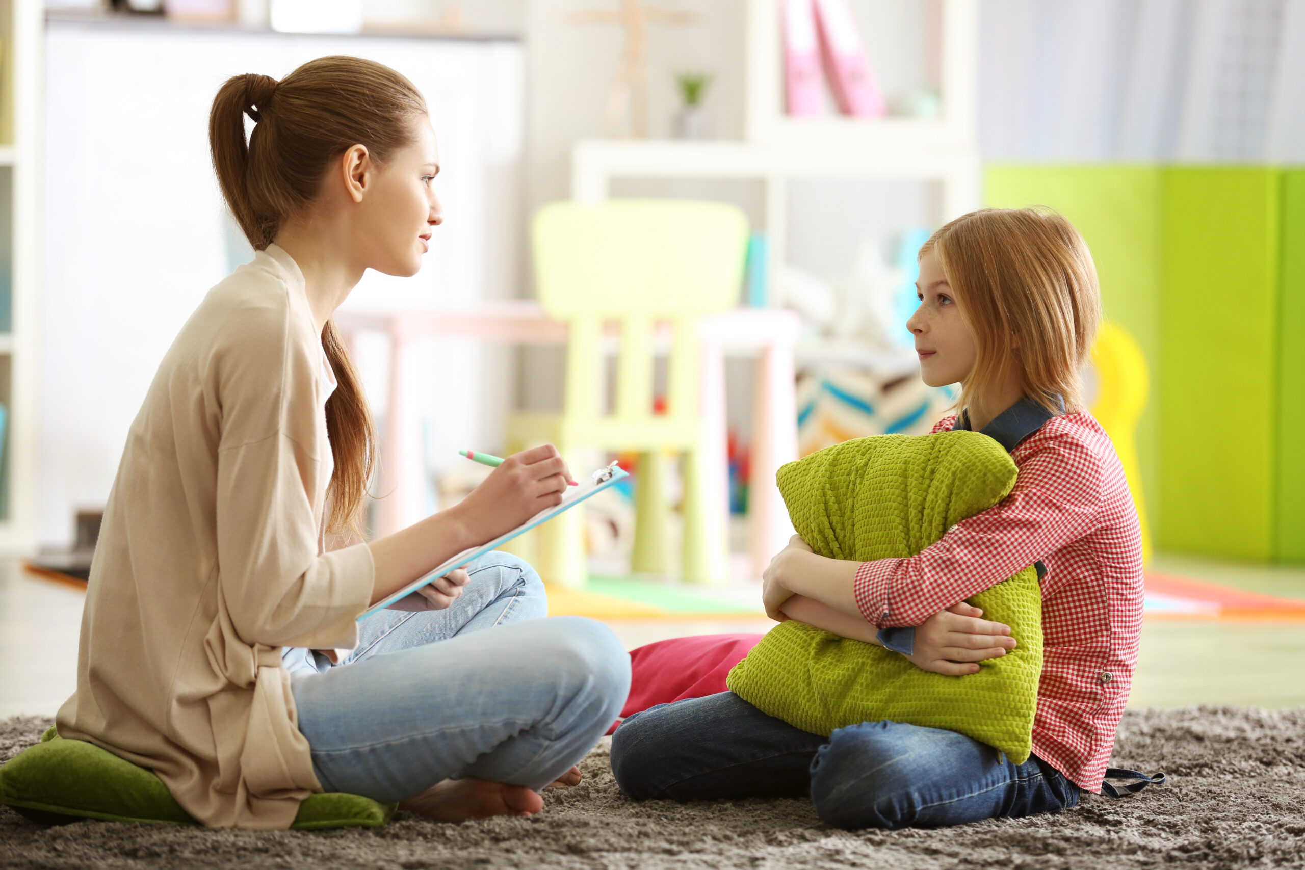 an image of a man sitting on a bed with his crying baby in front of him as he is talking on the phone with a concerned look on his face