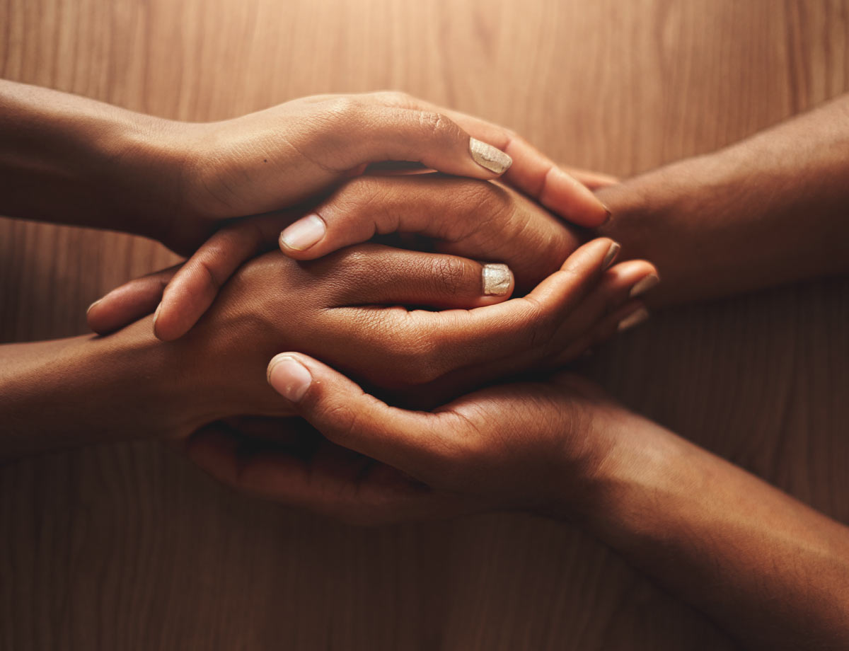 two pairs of hands holding each other over a table top