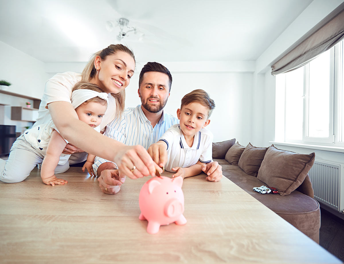 a family of four putting coins into a piggy bank in their kitchen