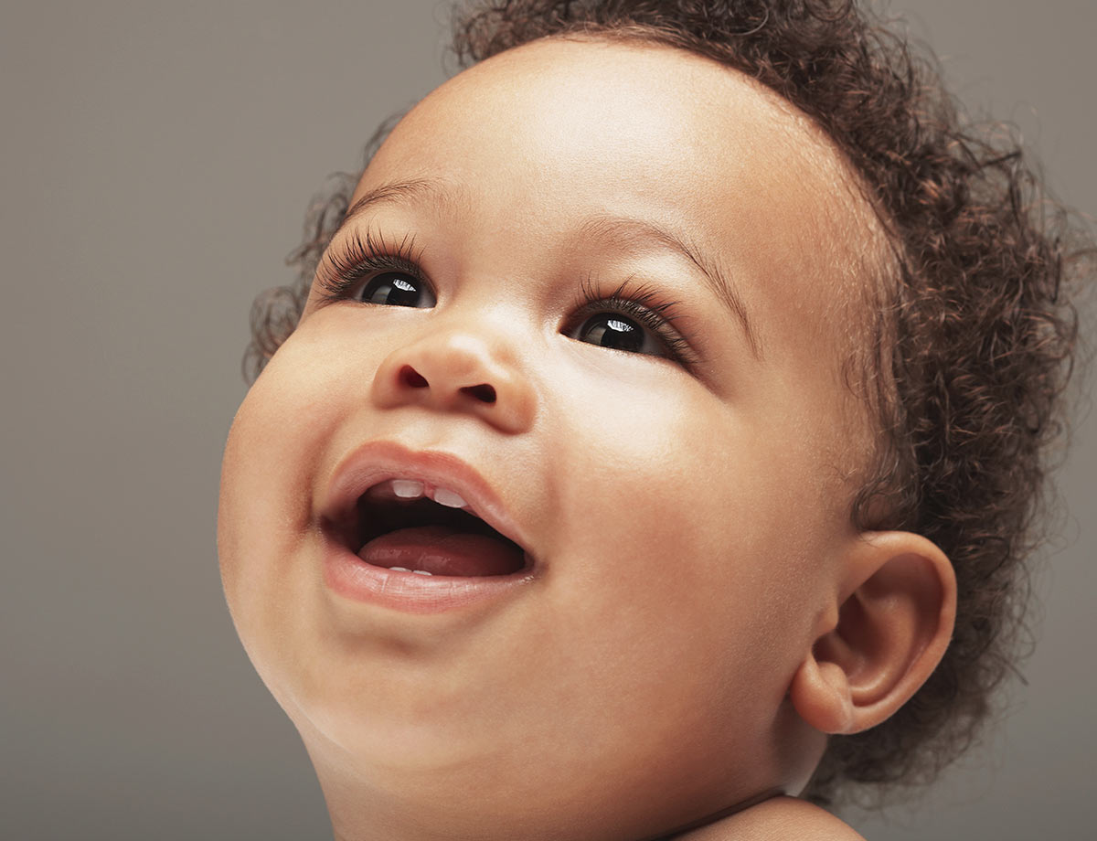 a baby with his front teeth looking up and smiling