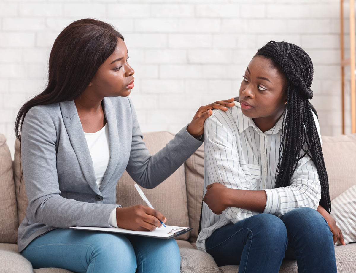 an older woman consoling a younger woman while they both sit together on the couch